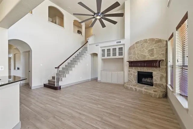 a view of a livingroom with wooden floor a fireplace and a ceiling fan