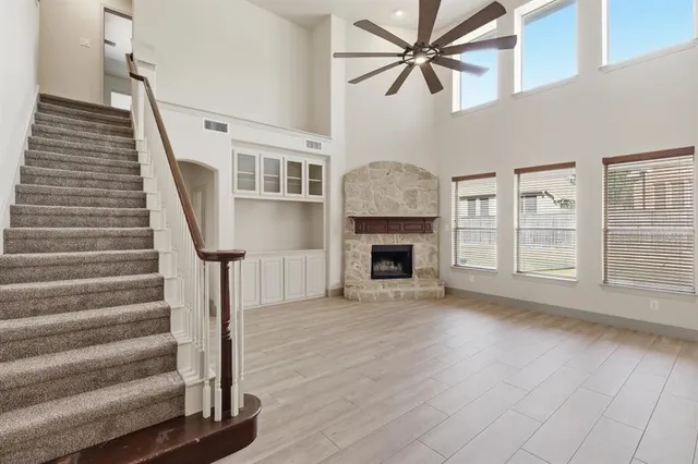 a view of a livingroom with wooden floor a ceiling fan and windows