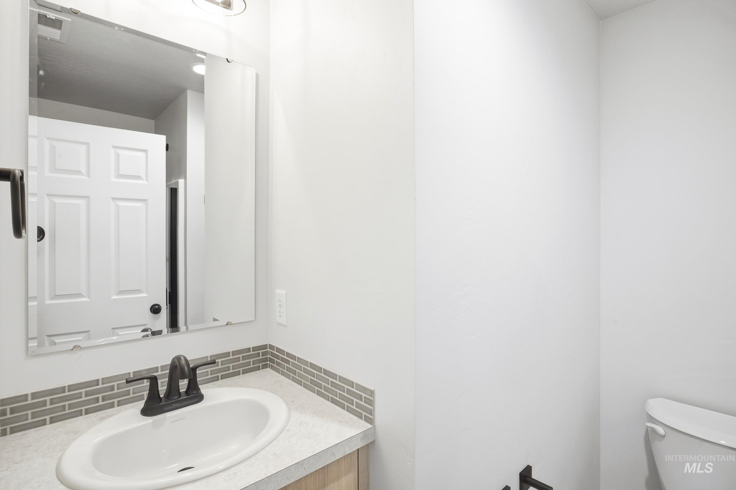 12841 Decatur Street Nampa, ID 83651 - Photo 12 of 30 Bathroom vanity featuring a white oval undermount sink, dark bronze two-handle faucet, and a light-toned countertop
