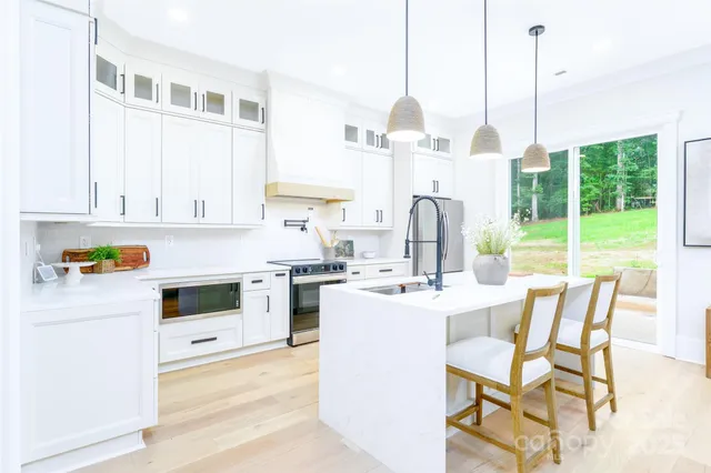 a kitchen with a stove a refrigerator and a view of living room