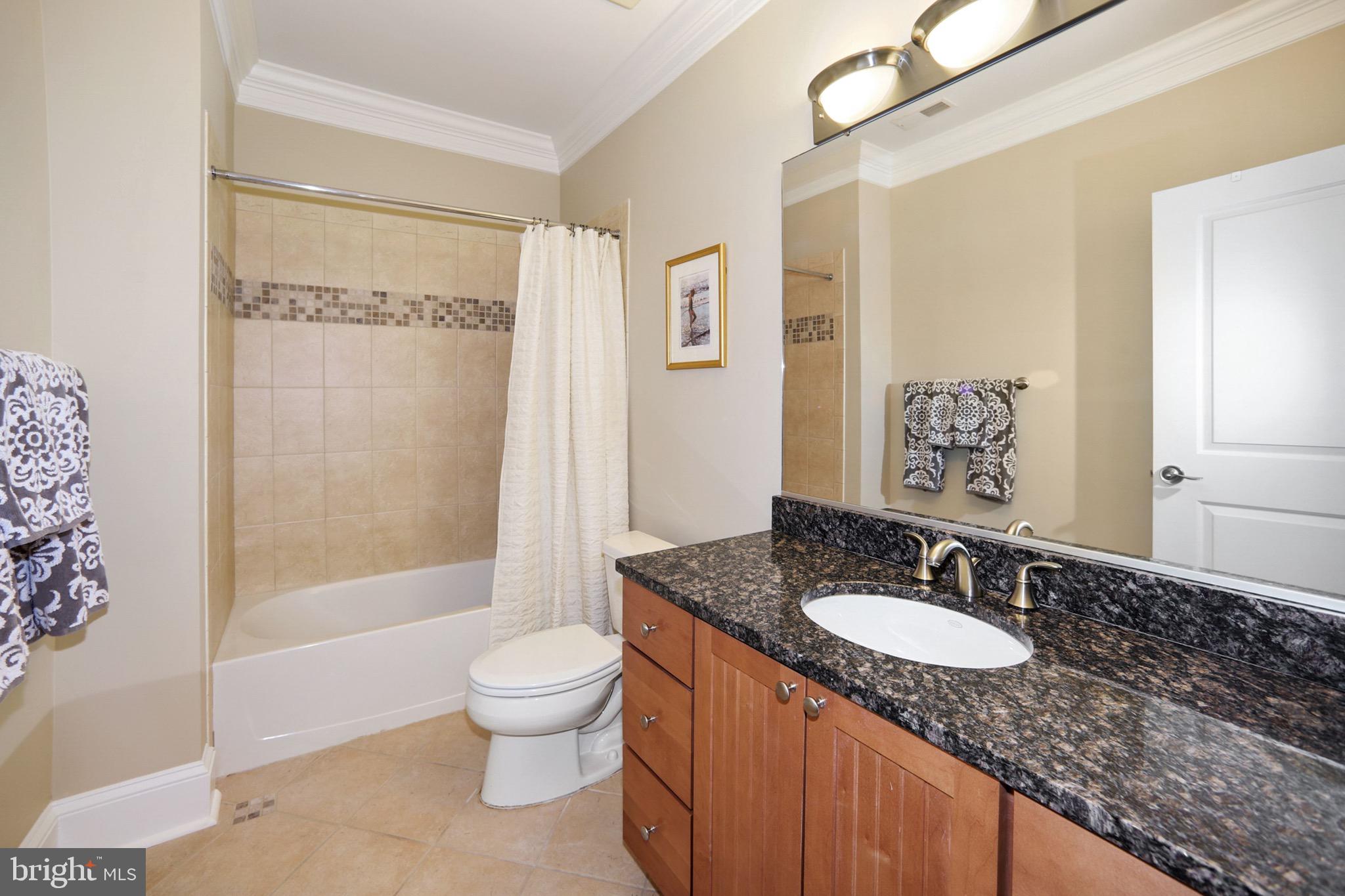 7117 Exfair Road Bethesda, MD 20814 - Photo 40 of 42 a bathroom with a granite countertop sink toilet a mirror and shower