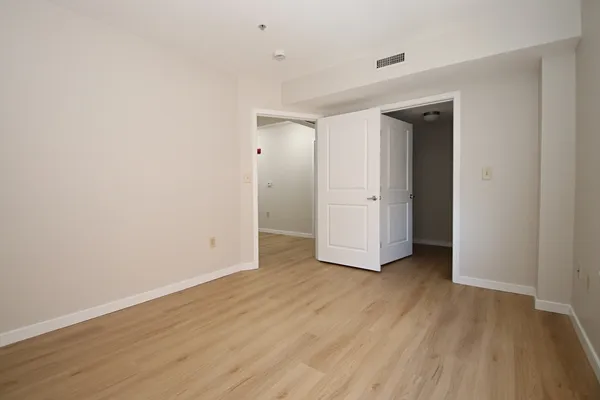 an empty room with wooden floor & closet and windows