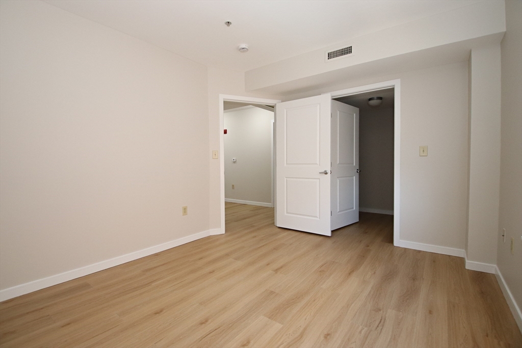 175 Cottage Street, Unit 501 Chelsea, MA 02150 - Photo 19 of 42 an empty room with wooden floor & closet and windows