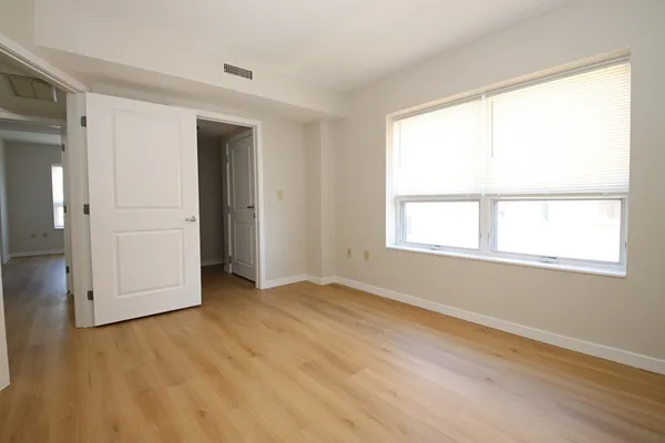 an empty room with wooden floor and windows