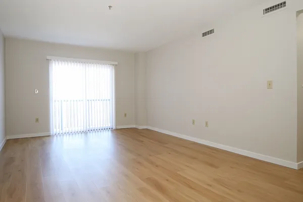 a view of an empty room with wooden floor and a window