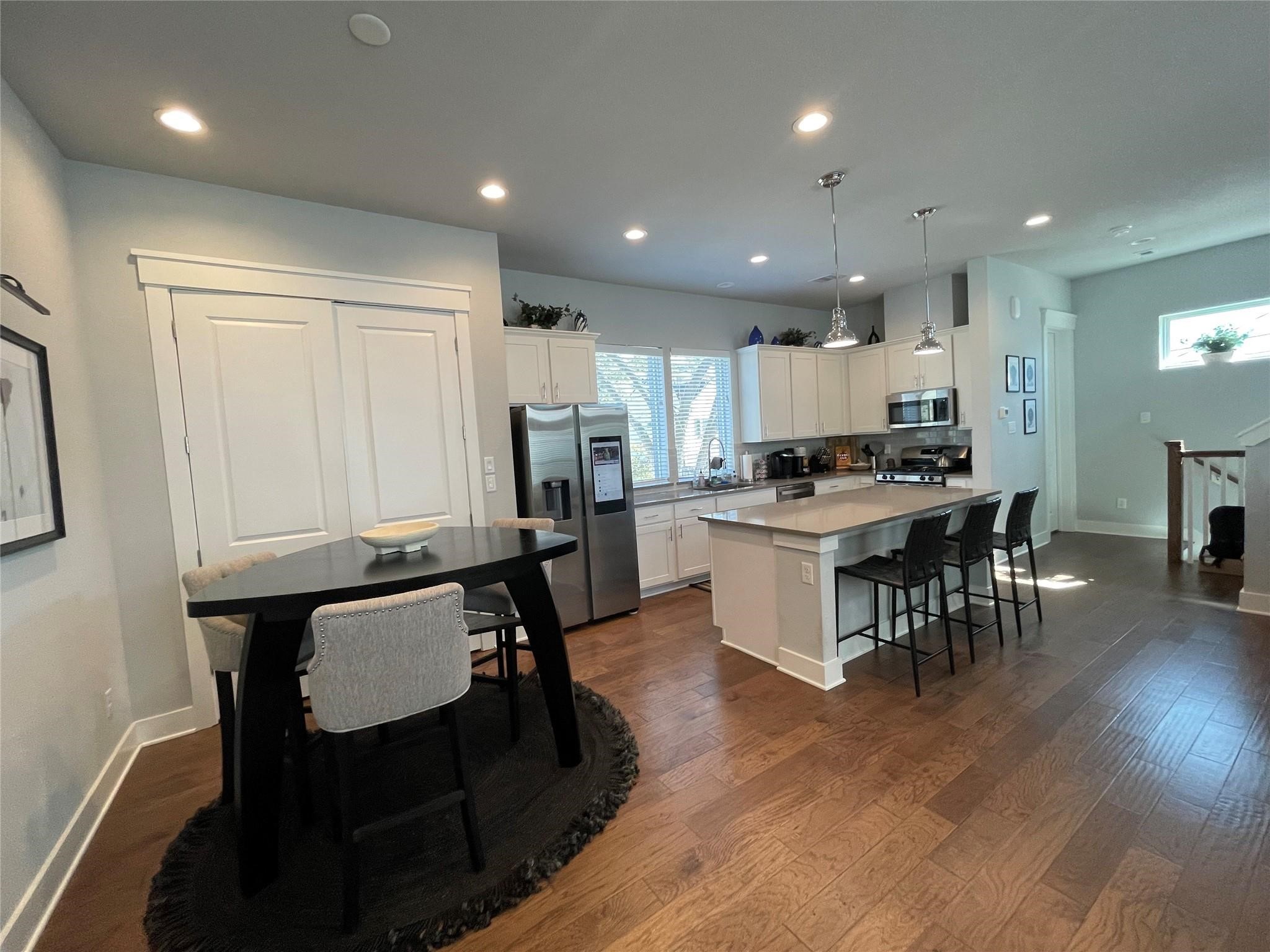 902 Martin Street, Unit A Houston, TX 77018 - Photo 8 of 21 a kitchen with stainless steel appliances a table chairs refrigerator and a stove top oven with wooden floor
