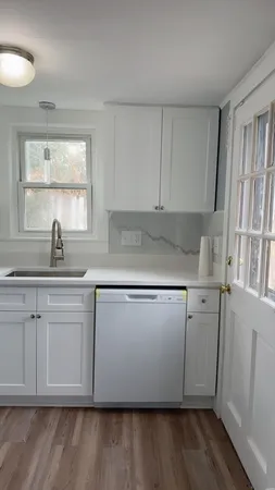 a kitchen with stainless steel appliances granite countertop a sink a stove a microwave a window and white cabinets
