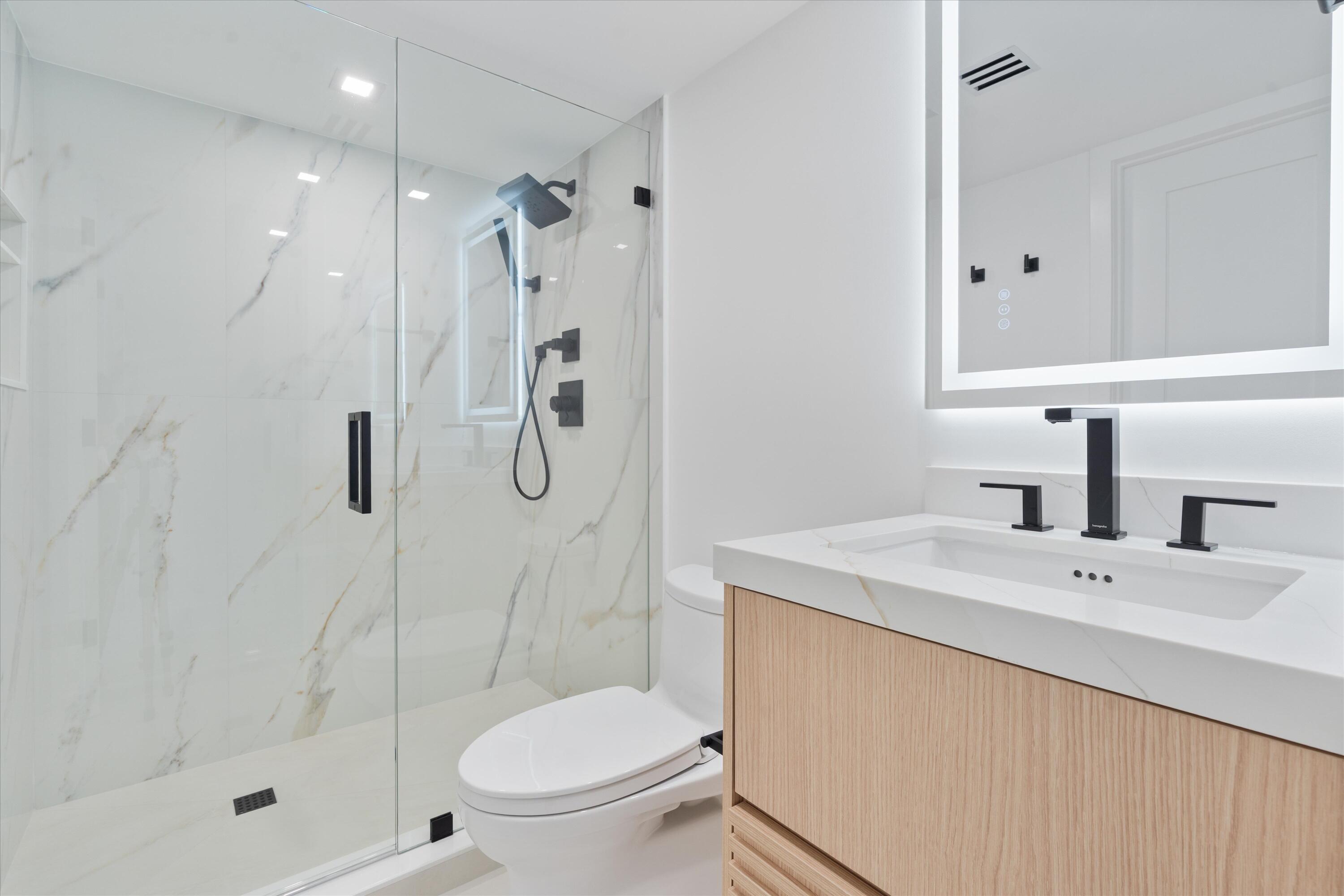 250 South Ocean Boulevard, Unit 3E & 3F Boca Raton, FL 33432 - Photo 29 of 46 a bathroom with a shower sink vanity mirror and toilet