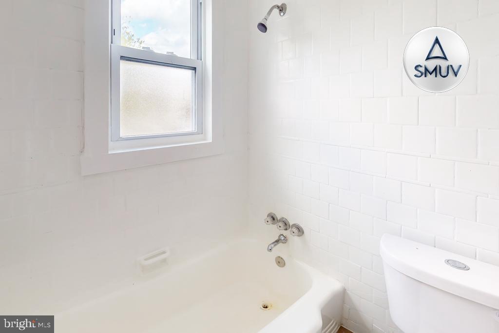 1605 Homestead Street, Unit 1 Baltimore, MD 21218 - Photo 11 of 18 a bath tub sitting next to a white toilet and a window