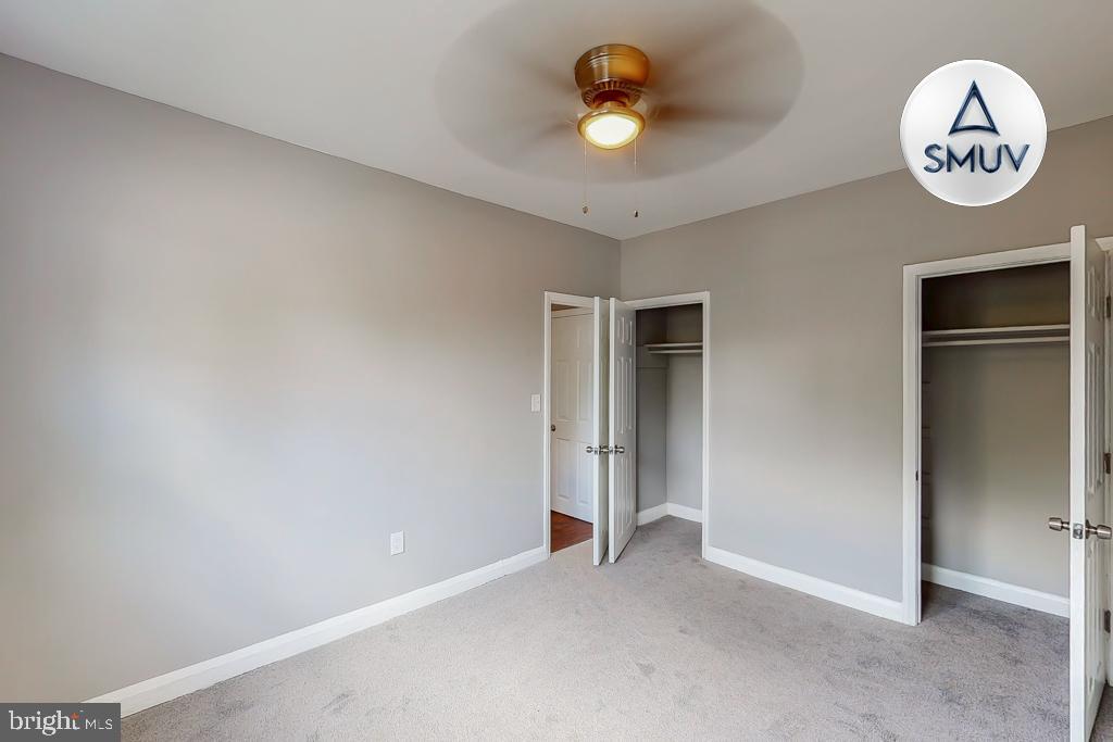 1605 Homestead Street, Unit 1 Baltimore, MD 21218 - Photo 7 of 18 an empty room with a large mirror and a ceiling fan