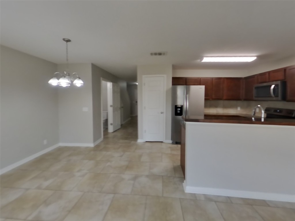 1027 Trail Driver Cove Georgetown, TX 78626 - Photo 4 of 17 Kitchen featuring dark countertops, appliances with stainless steel finishes, pendant lighting, a chandelier, and a peninsula