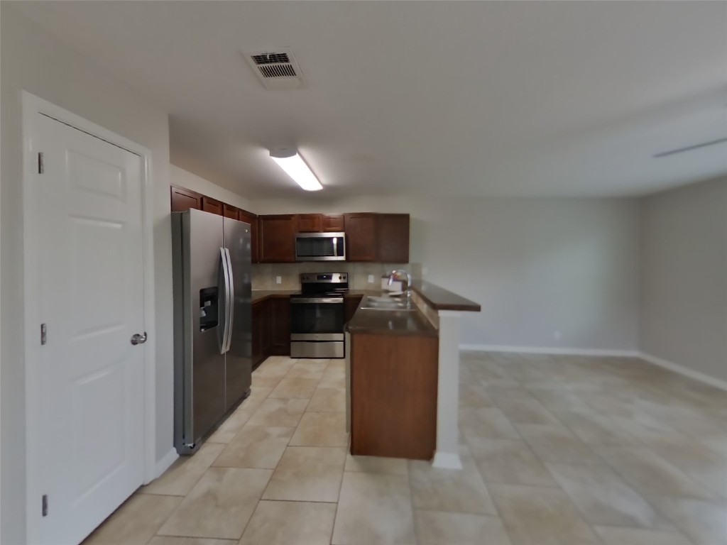 1027 Trail Driver Cove Georgetown, TX 78626 - Photo 15 of 17 Kitchen with dark countertops, stainless steel appliances, a peninsula, and open floor plan