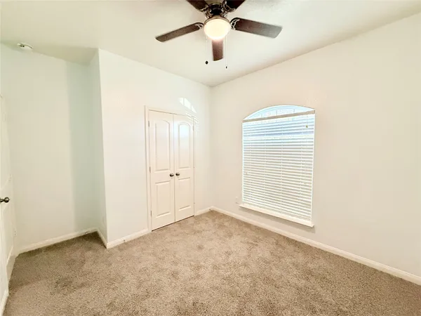 an empty room with a ceiling fan and carpet