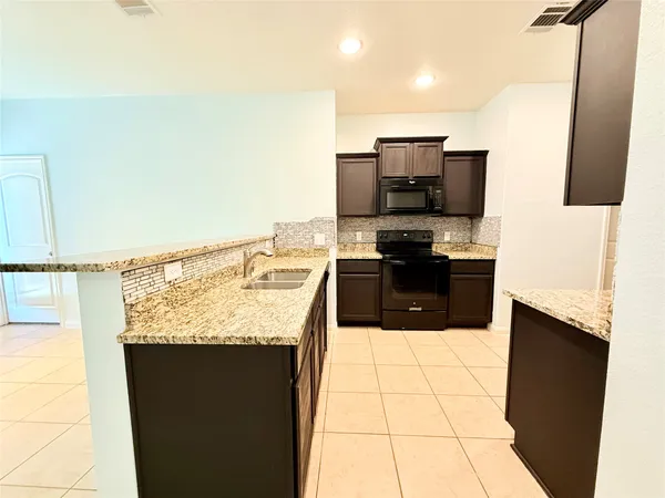 a kitchen with stainless steel appliances kitchen island granite countertop a sink stove and refrigerator