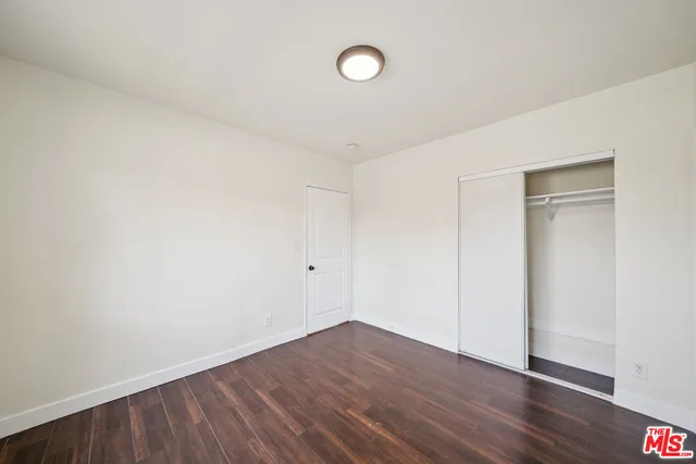 a view of an empty room with wooden floor and fan