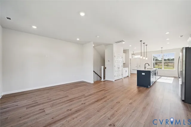 a view of a kitchen with kitchen island a sink wooden floor and a large window