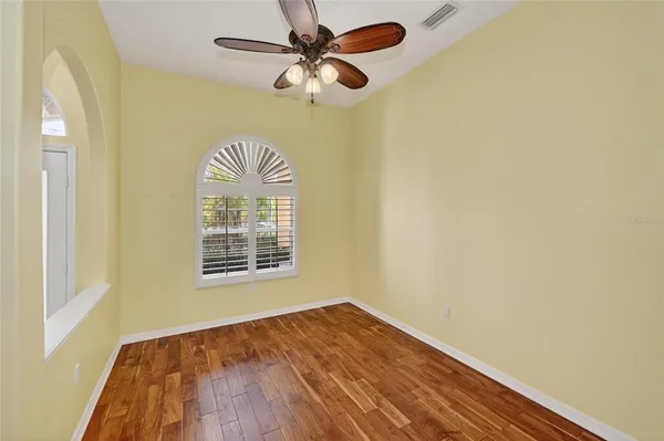 a view of empty room with wooden floor and fan