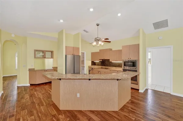 a large kitchen with stainless steel appliances kitchen island a large counter top and a wooden floors