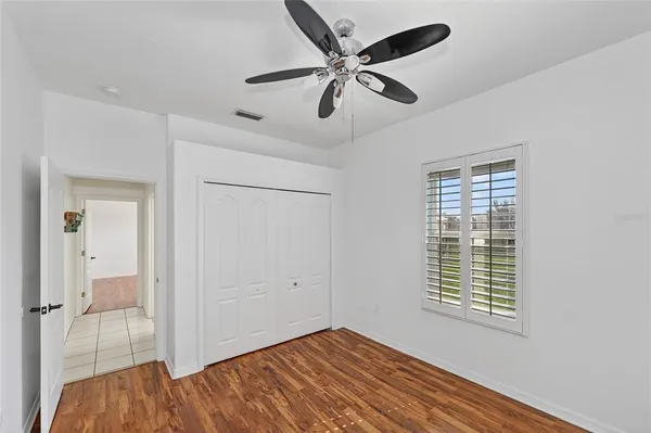 a view of empty room with wooden floor and fan