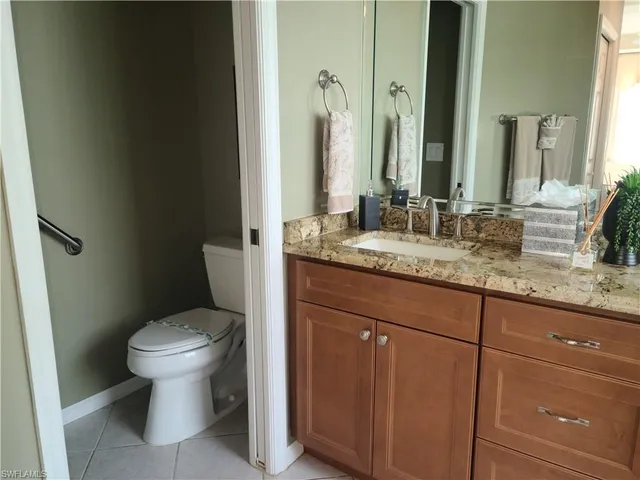 a bathroom with a granite countertop toilet sink and mirror