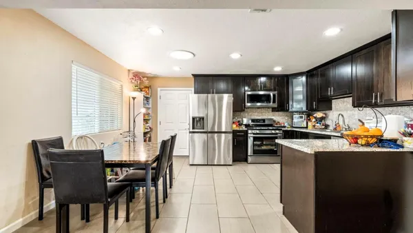 a kitchen with stainless steel appliances kitchen island granite countertop a stove a refrigerator a sink a dining table and chairs