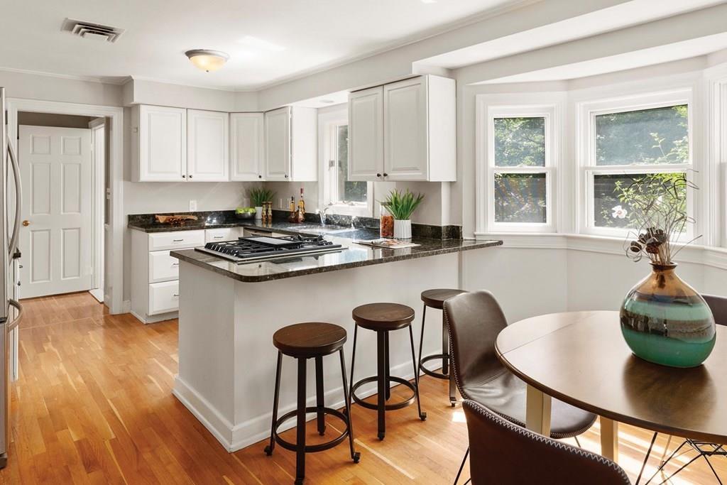 7 Dorothy Road Newton, MA 02459 - Photo 8 of 23 a kitchen with stainless steel appliances granite countertop a stove a refrigerator a kitchen island with a dining table and chairs