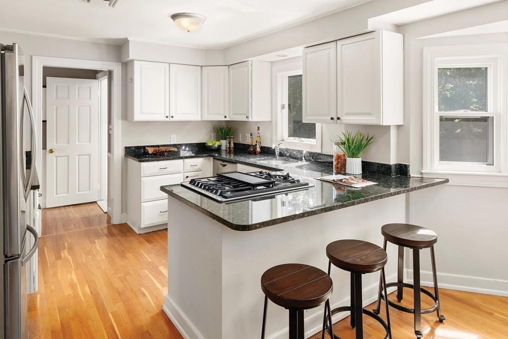 7 Dorothy Road Newton, MA 02459 - Photo 9 of 23 a kitchen with granite countertop a stove a sink dishwasher and white cabinets with wooden floor