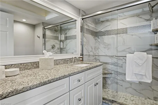 a bathroom with a granite countertop sink a mirror and shower