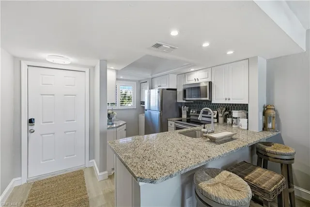 a kitchen with granite countertop kitchen island stainless steel appliances a sink stove and refrigerator