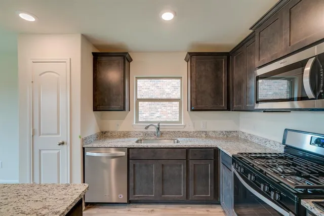 a kitchen with stainless steel appliances granite countertop a refrigerator stove microwave and sink