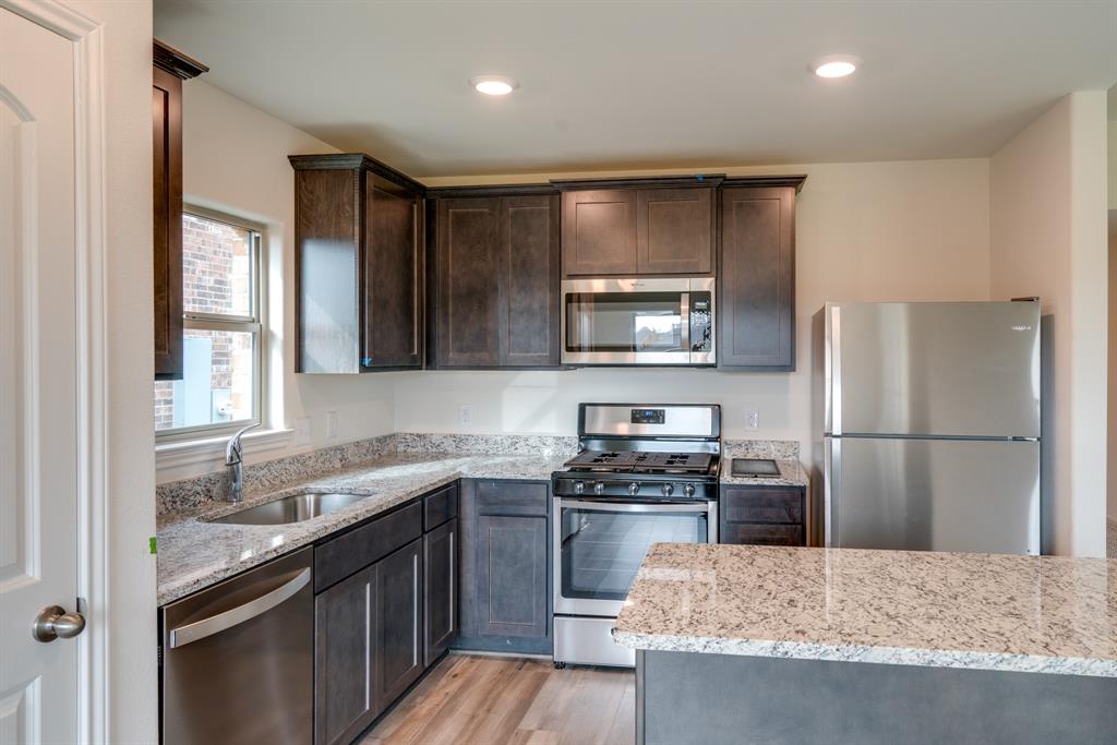 232 Micah Lane Ferris, TX 75125 - Photo 16 of 32 a kitchen with kitchen island granite countertop stainless steel appliances a sink stove refrigerator and cabinets