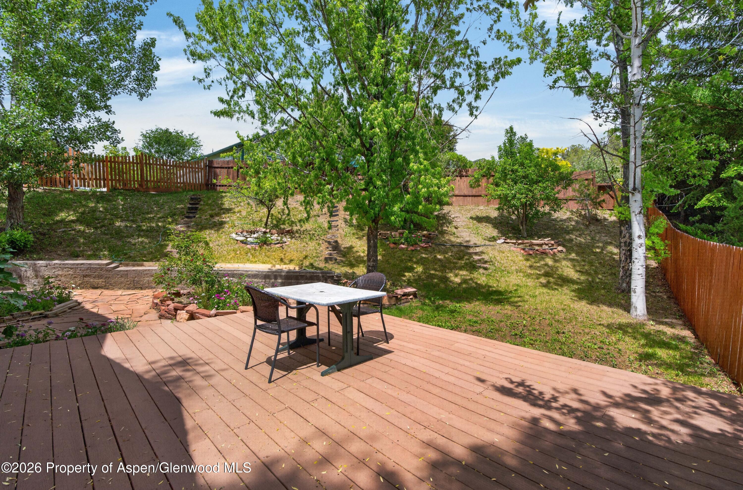 608 Lariat Loop New Castle, CO 81647 - Photo 26 of 32 a backyard of a house with table and chairs floor to ceiling window and wooden fence