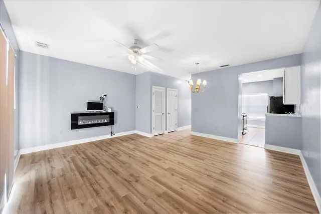 a view of a livingroom with wooden floor and a kitchen space