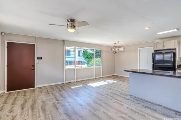 a view of a kitchen with wooden floor a ceiling fan and windows