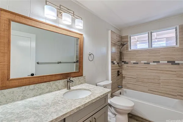 a bathroom with a granite countertop sink toilet mirror and bathtub