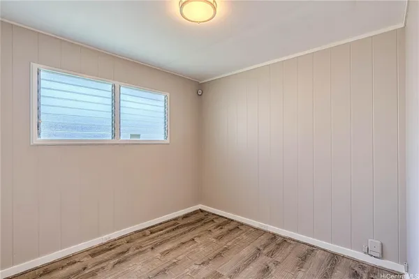a view of an empty room with wooden floor and window