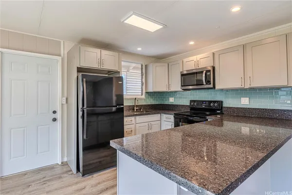 a kitchen with kitchen island granite countertop a refrigerator and a sink