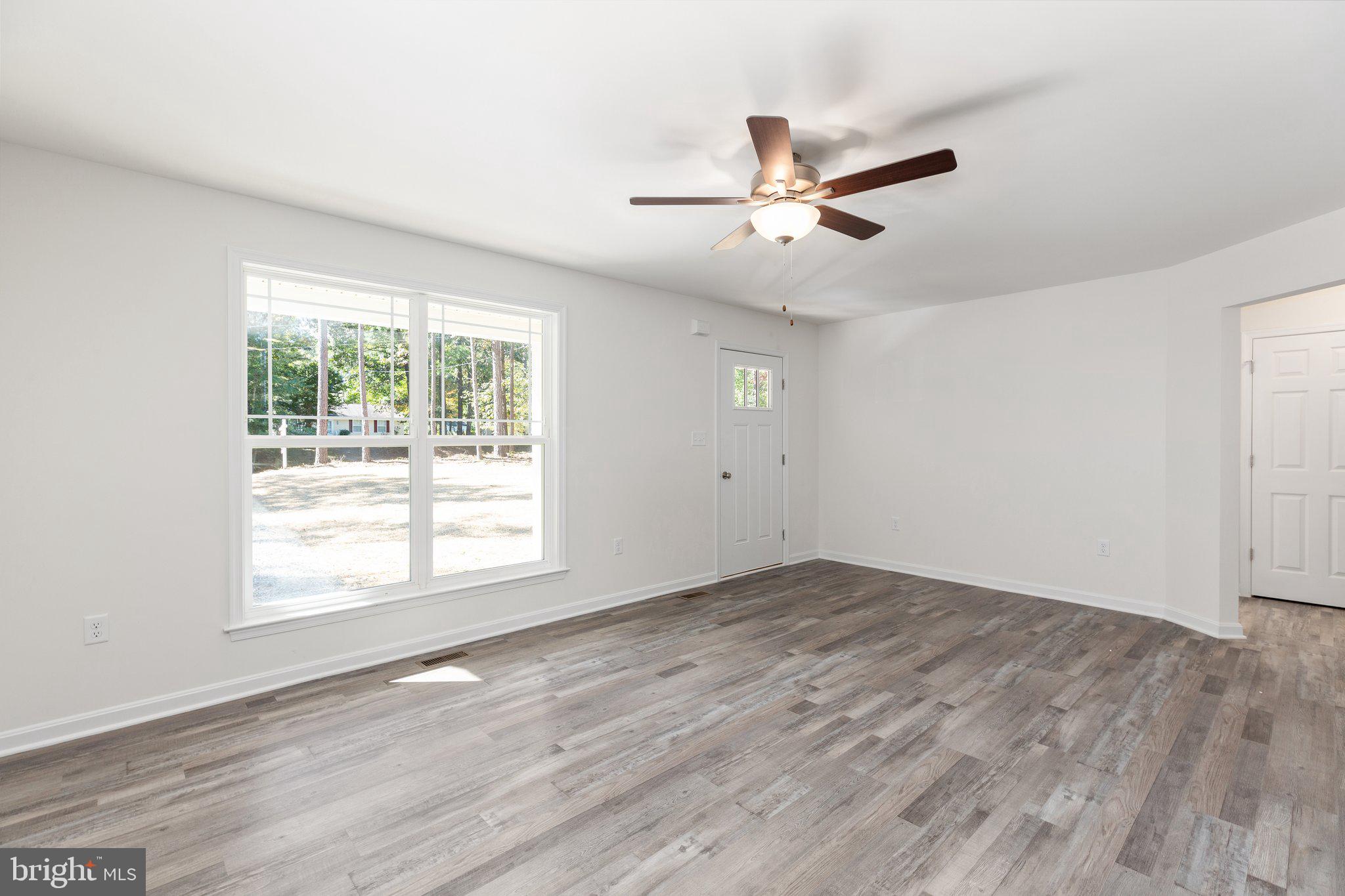 69 Pinewood Lane, Unit L18 Colonial Beach, VA 22443 - Photo 2 of 28 an empty room with wooden floor fan and windows
