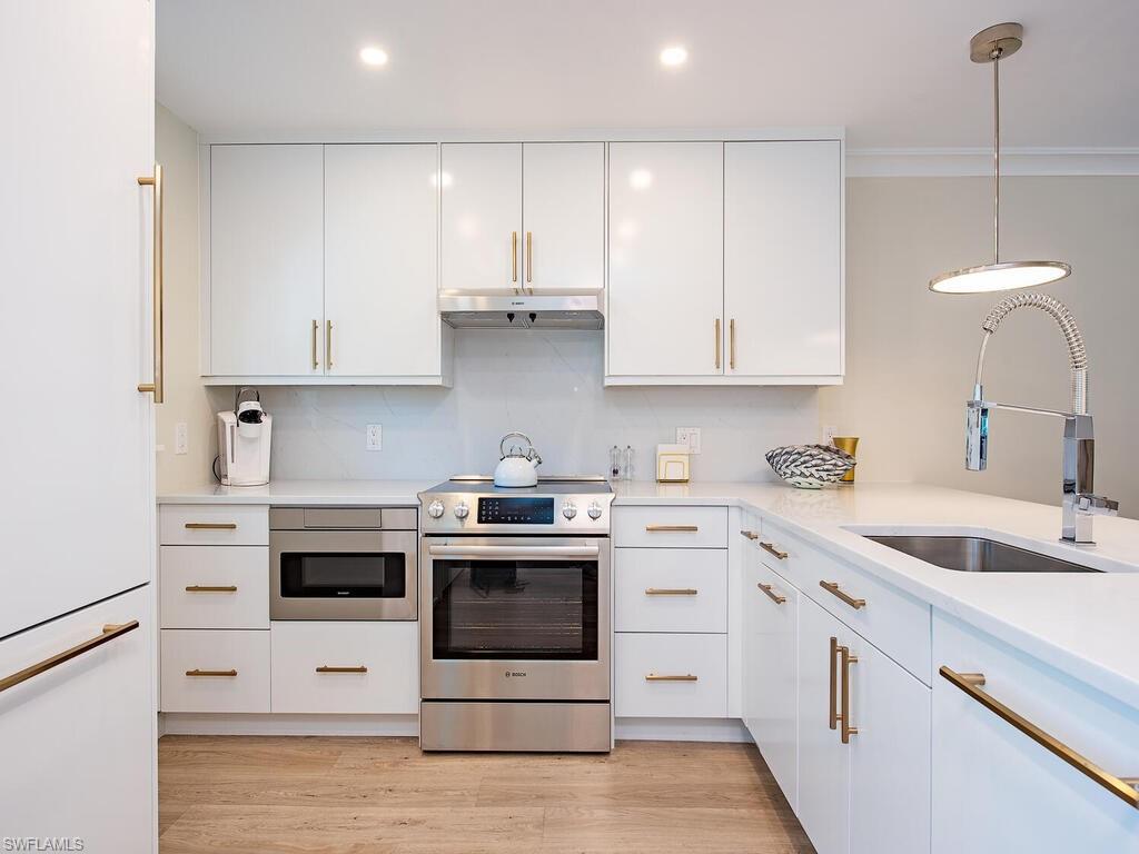 536 2nd Street South, Unit 536 Naples, FL 34102 - Photo 2 of 14 Kitchen with stainless steel appliances, white cabinetry, tasteful backsplash, pendant lighting, and crown molding