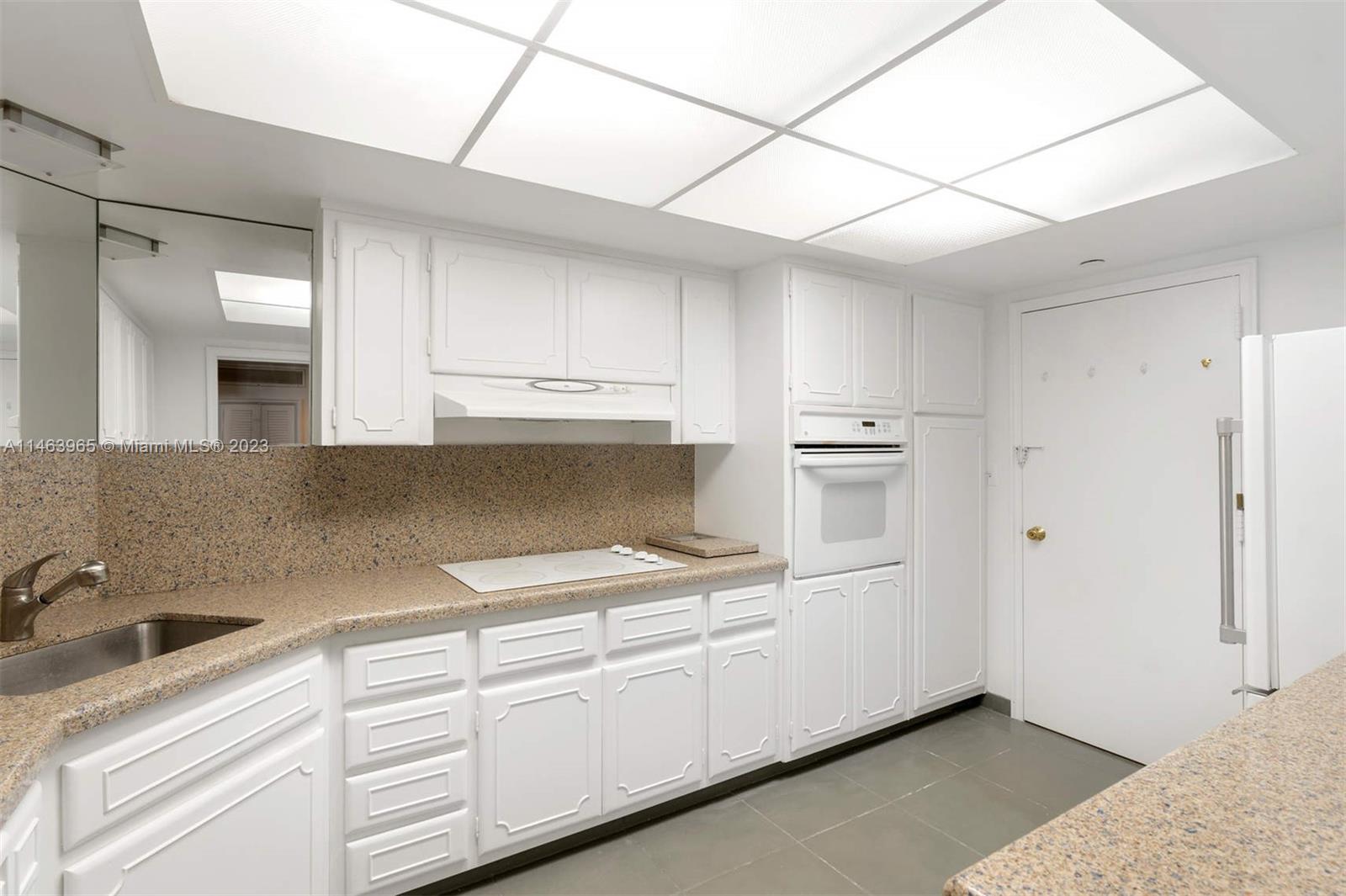 200 Ocean Ln Drive, Unit 703 Key Biscayne, FL 33149 - Photo 7 of 26 a kitchen with granite countertop white cabinets and white appliances