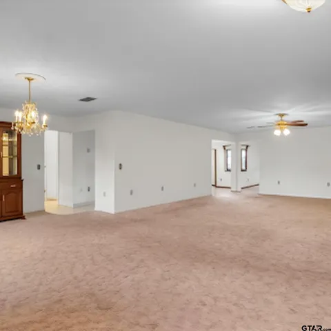 a view of an empty room with chandelier fan