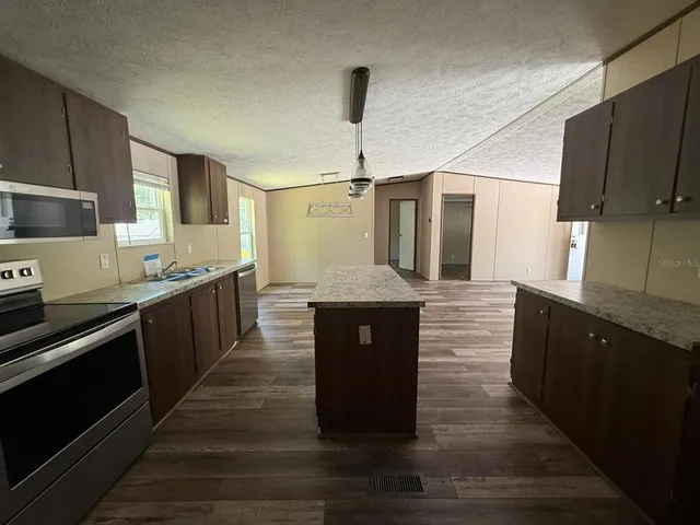 a kitchen with stainless steel appliances granite countertop a stove a sink and a refrigerator