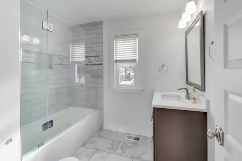 a bathroom with a bathtub sink vanity and mirror
