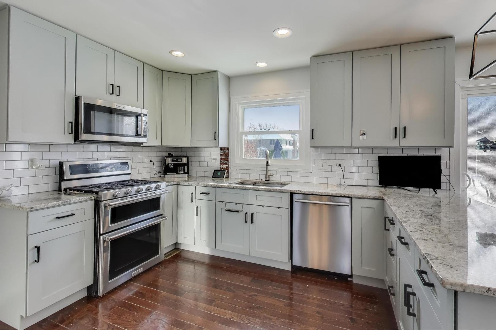 1565 Brittany Lane Hoffman Estates, IL 60192 - Photo 2 of 26 a kitchen with stainless steel appliances granite countertop a stove top oven a sink a microwave and cabinets