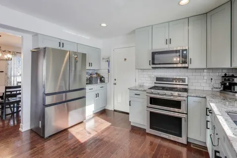 a kitchen with cabinets stainless steel appliances and wooden floor