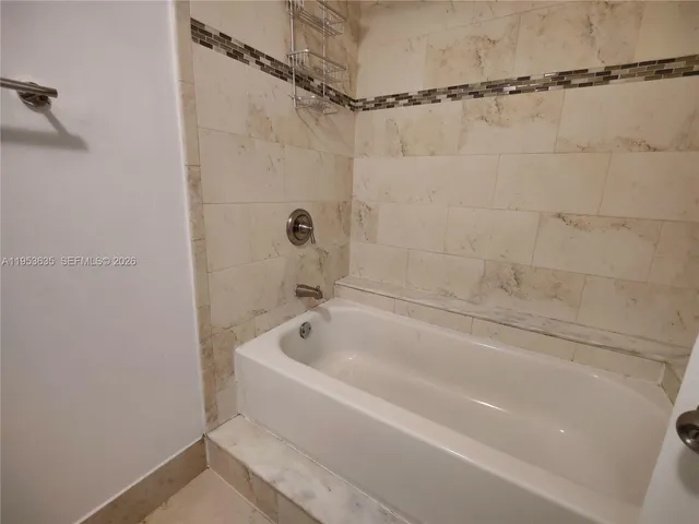 a white bath tub sitting next to a white sink and vanity