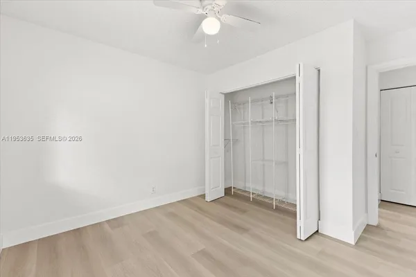 an empty room with wooden floor and fan chandelier
