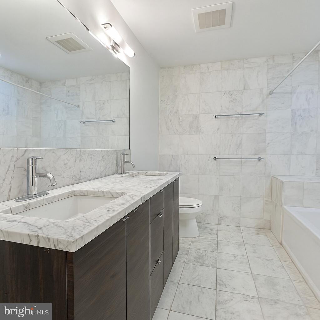 112 Market Street, Unit 4 Philadelphia, PA 19106 - Photo 7 of 15 a bathroom with a granite countertop sink a toilet and shower