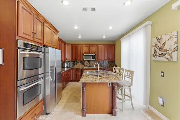 a kitchen with stainless steel appliances kitchen island granite countertop a refrigerator and a stove top oven