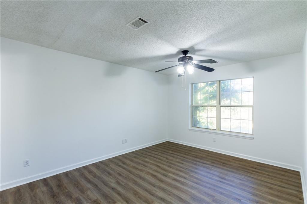 4908 Tarleton Drive Southwest Lilburn, GA 30047 - Photo 13 of 41 an empty room with wooden floor and windows